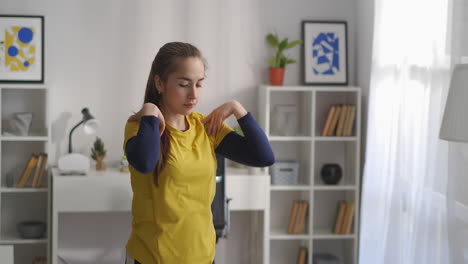young-woman-is-doing-exercises-for-shoulders-and-neck-warming-muscles-at-morning-workout-rotating-arms-forward-and-back-medium-portrait